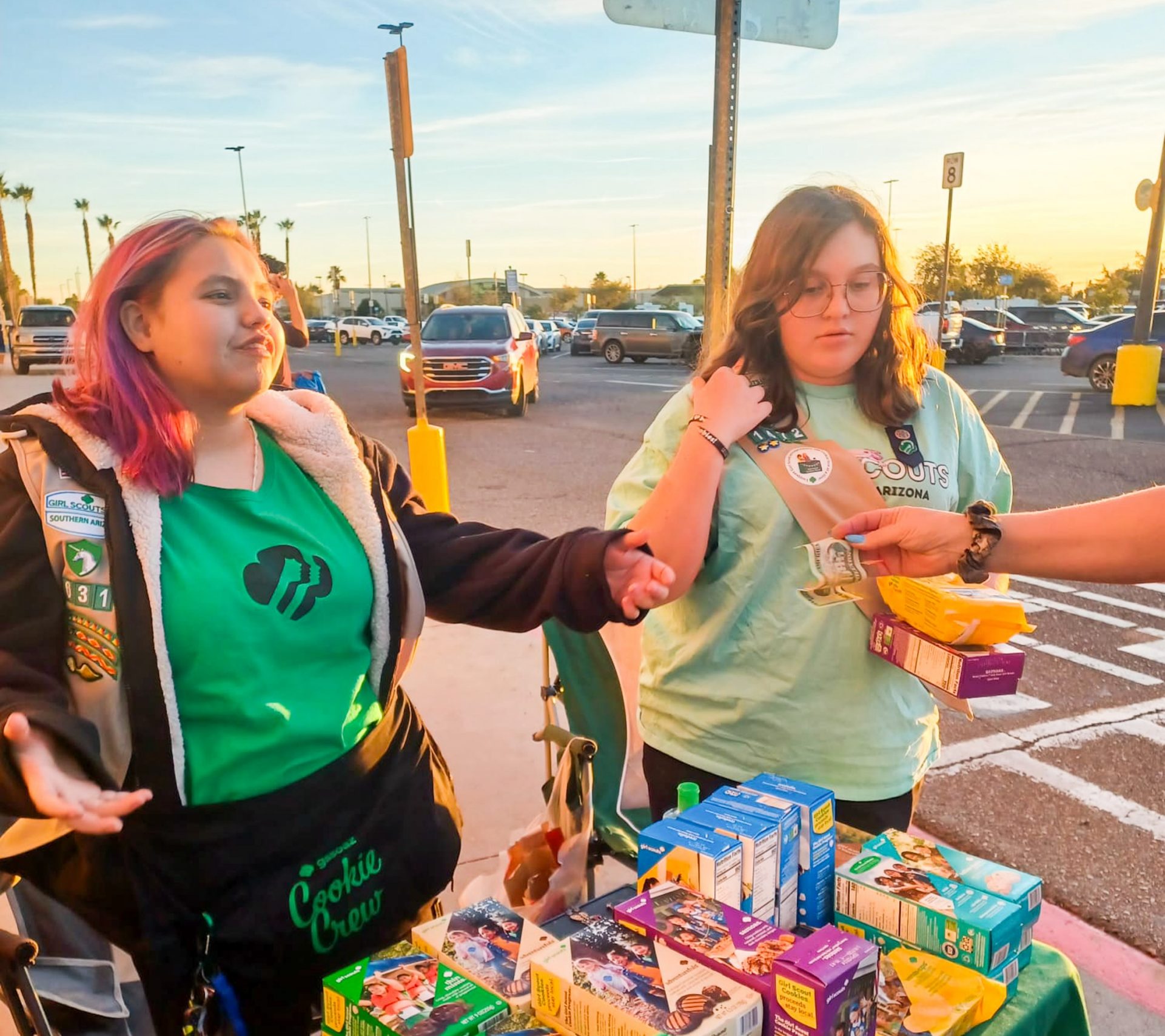 older girl scouts behind a cookie booth