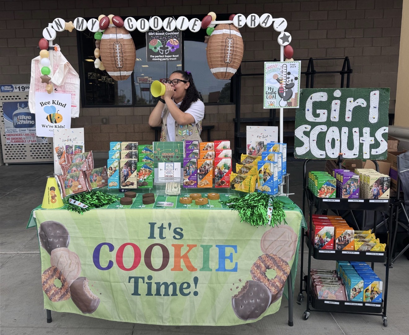 older girl scouts behind a cookie booth