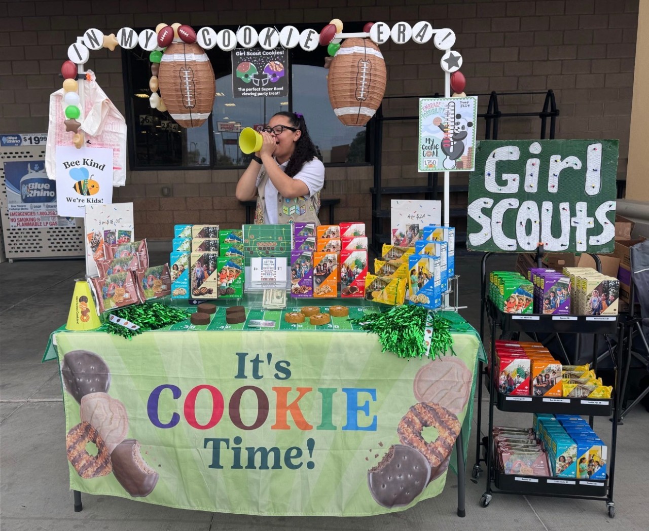 older girl scouts behind a cookie booth