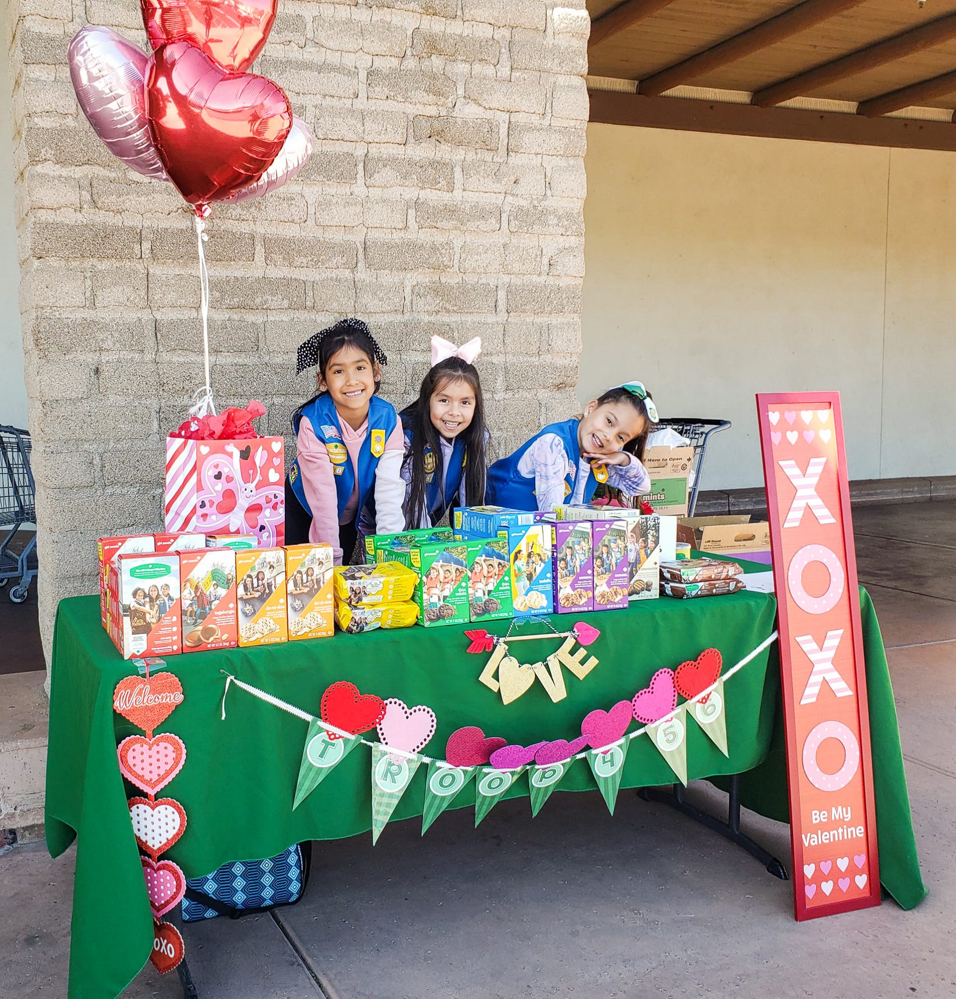 girl scout daisies smiling behind their cookie booth