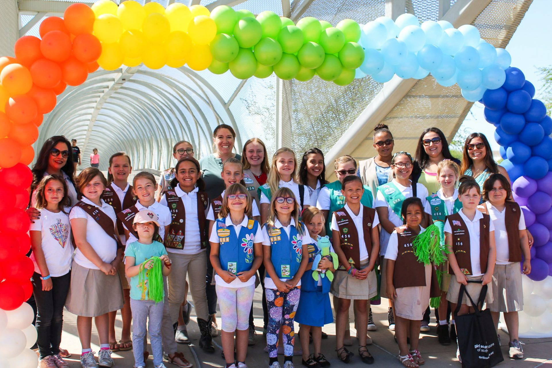 troops gathered beneath rainbow balloons to celebrate bridging