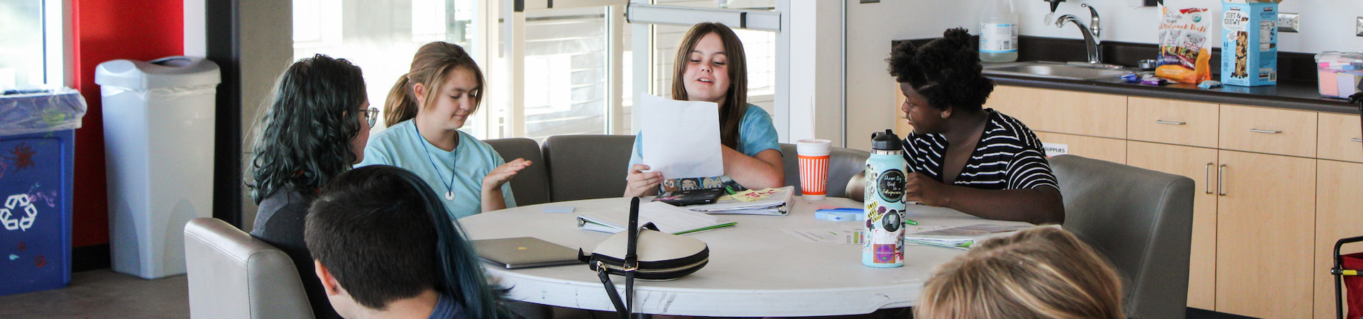  girl scouts sitting around a table talking 