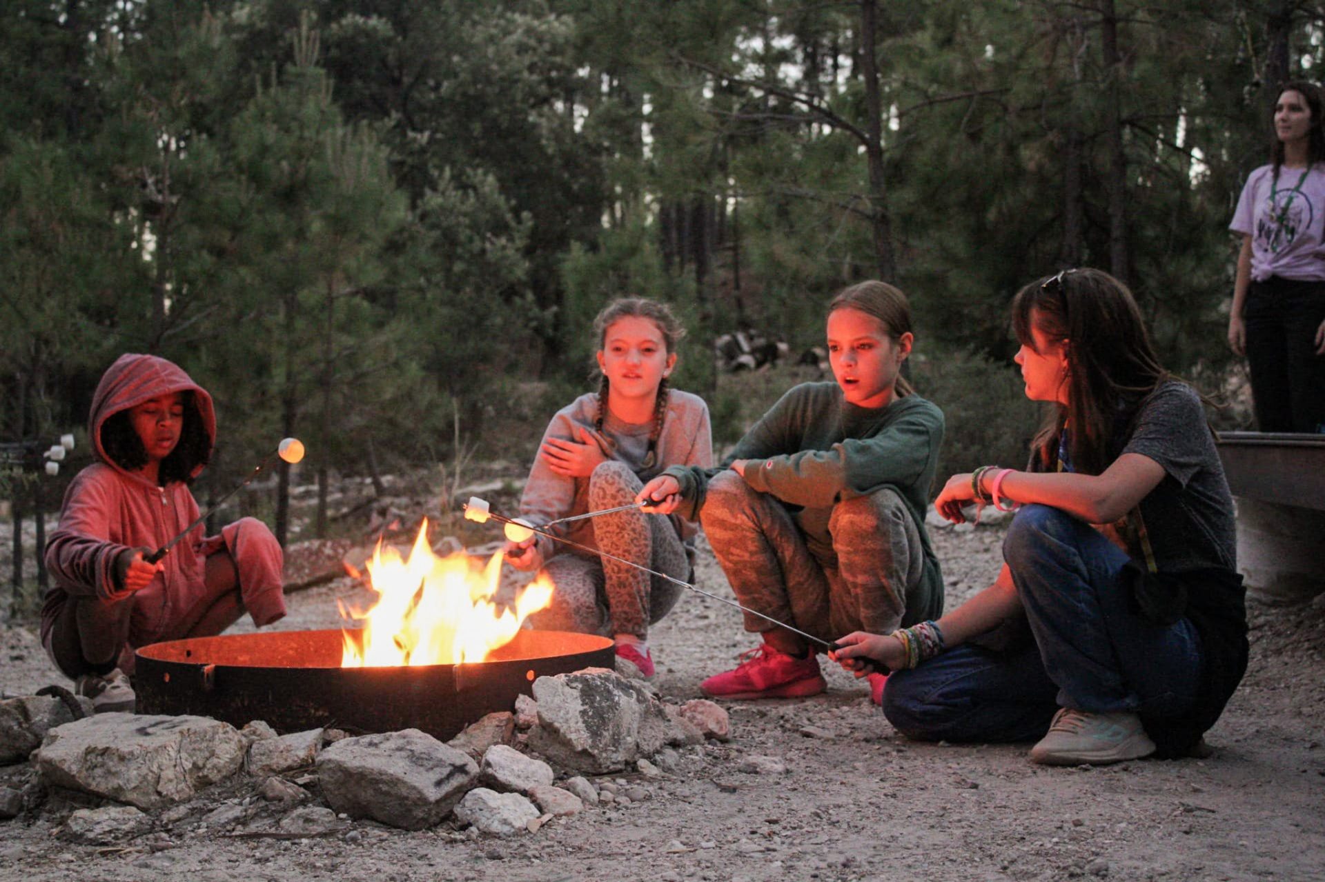 girl scouts roasting smores around a camp fire