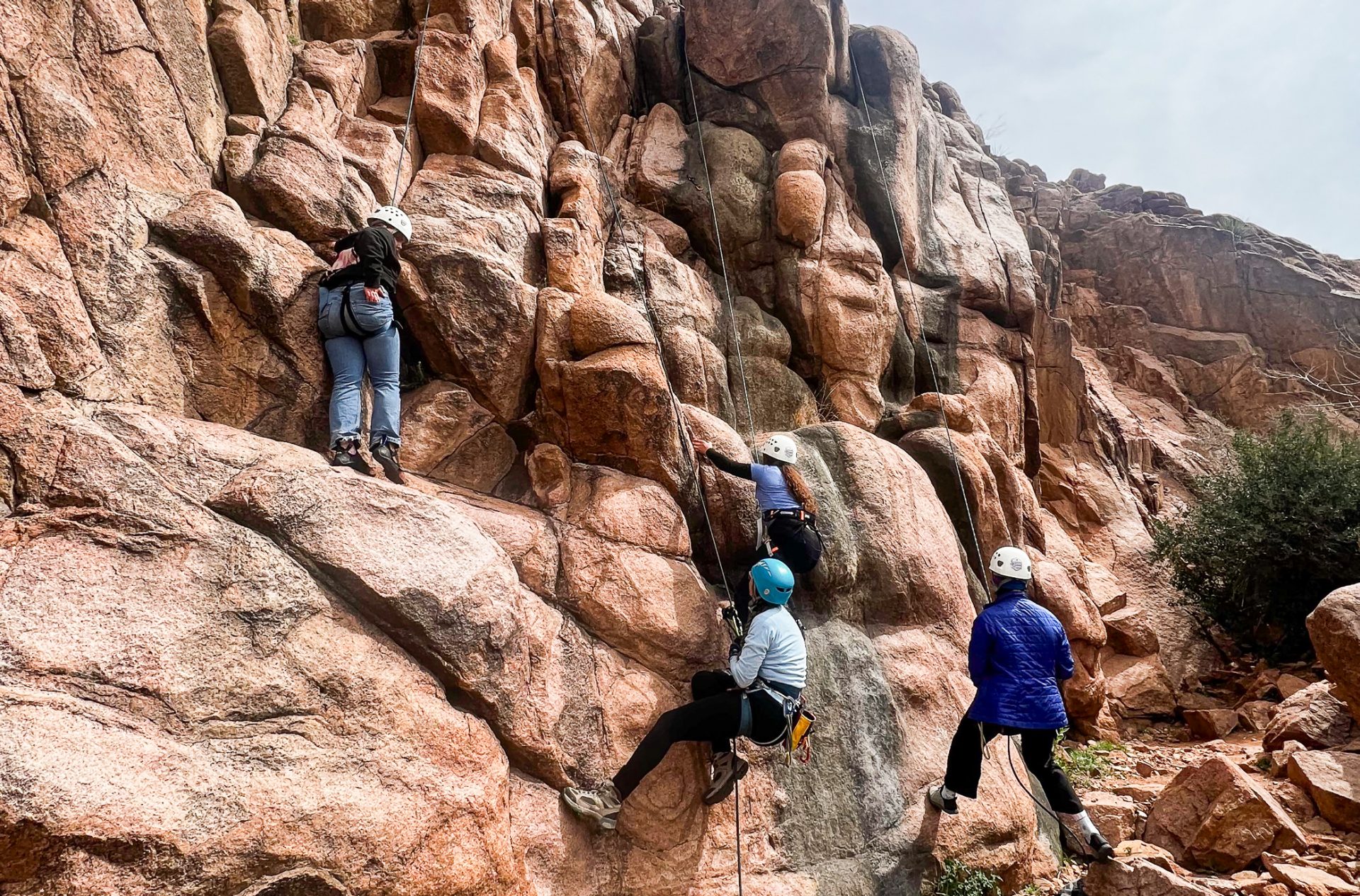 girl scouts rock climbing with helmets and ropes