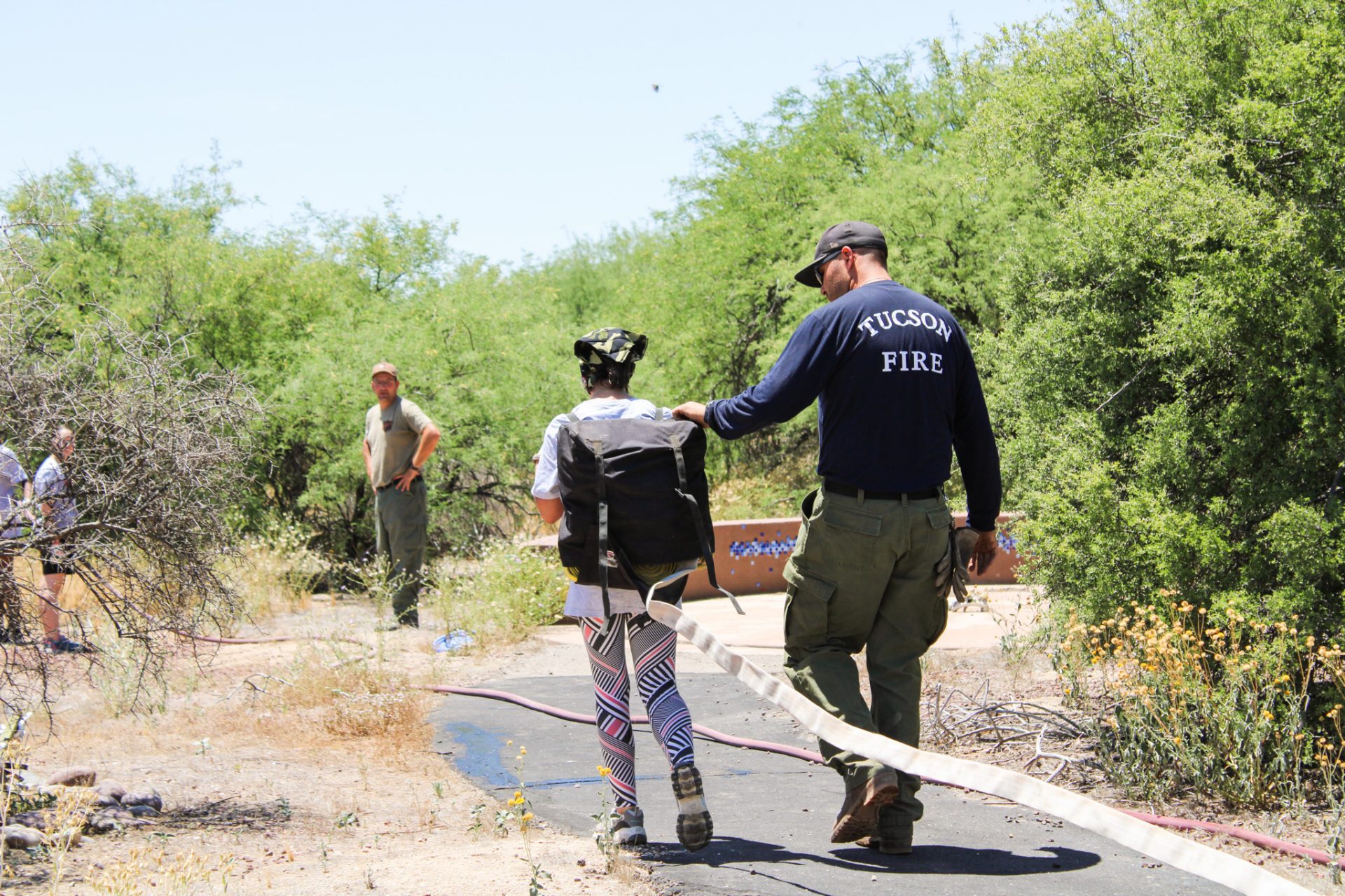 girl scout carrying water hose rope with the help of tucson fire department